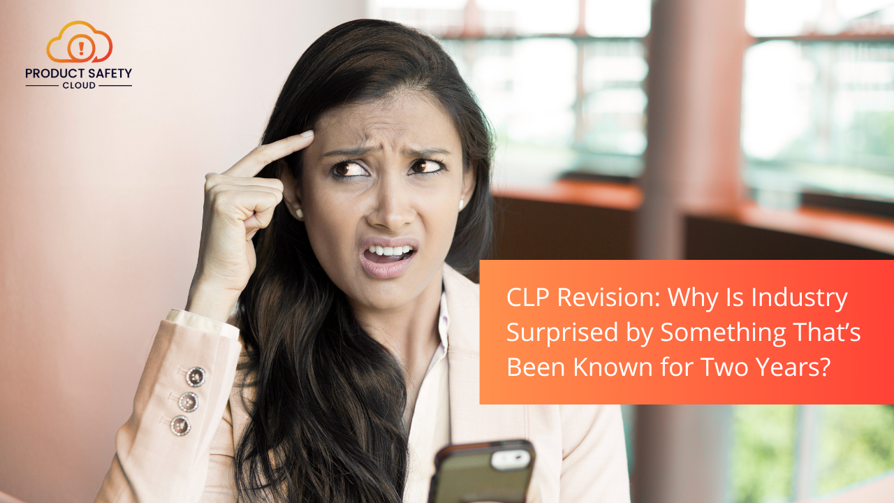 Verwarde vrouw in een kantooromgeving kijkt opzij terwijl ze met haar vinger naar haar hoofd wijst, met een smartphone in de hand. Rechts in beeld staat een oranje tekstvak met de tekst: &lsquo;CLP Revision: Why Is Industry Surprised by Something That&rsquo;s Been Known for Two Years?&rsquo; en linksboven het logo van Product Safety Cloud.